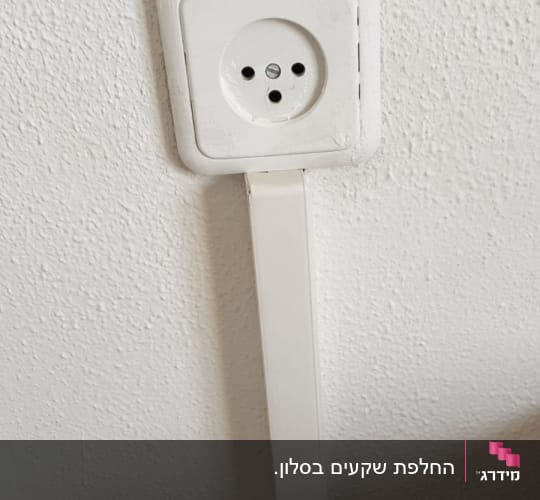 שקע חשמל עם כבל לבן על קיר